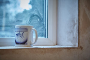 closeup of a dirty mug on a window sill in the building site of a kitchen extension in progress with a window visible behind